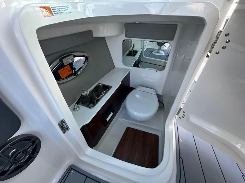 Slide: The Image of 2023 Chaparral 250 OSX boat interior with compact bathroom, sink, and toilet. - 26