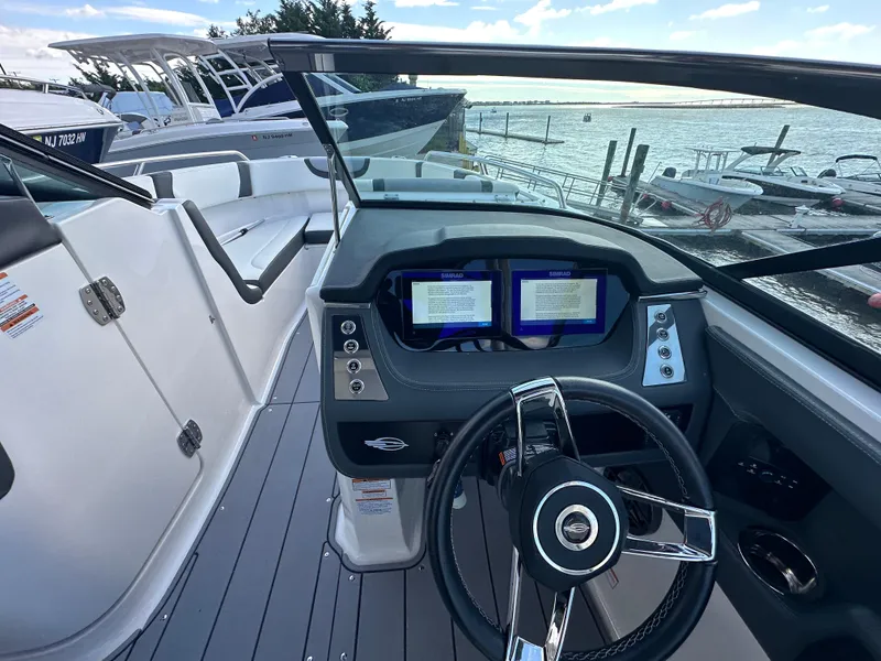 Slide: The Image of 2023 Chaparral 250 OSX boat cockpit with modern dashboard and steering wheel, docked by the water. - 29