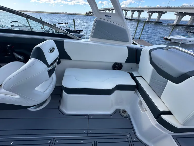 Slide: The Image of 2023 Chaparral 250 OSX boat interior with seating, near a bridge and waterfront. - 31