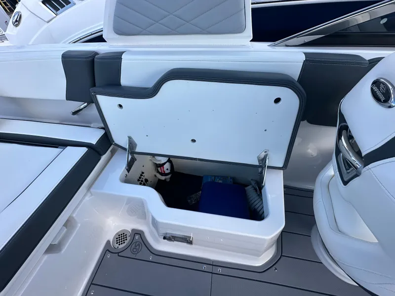 Slide: The Image of 2023 Chaparral 250 OSX boat storage compartment with open lid, showcasing interior space. - 34