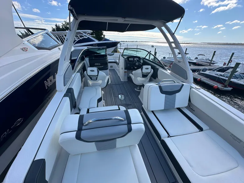 Slide: The Image of 2023 Chaparral 250 OSX boat with spacious seating, docked by the water. - 36