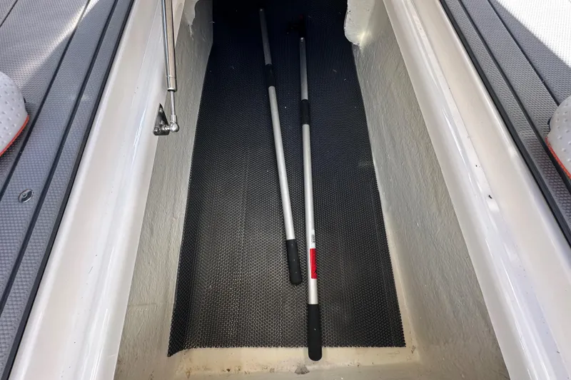 Slide: The Image of Storage compartment of 2023 Chaparral 250 OSX boat with two paddles inside. - 42