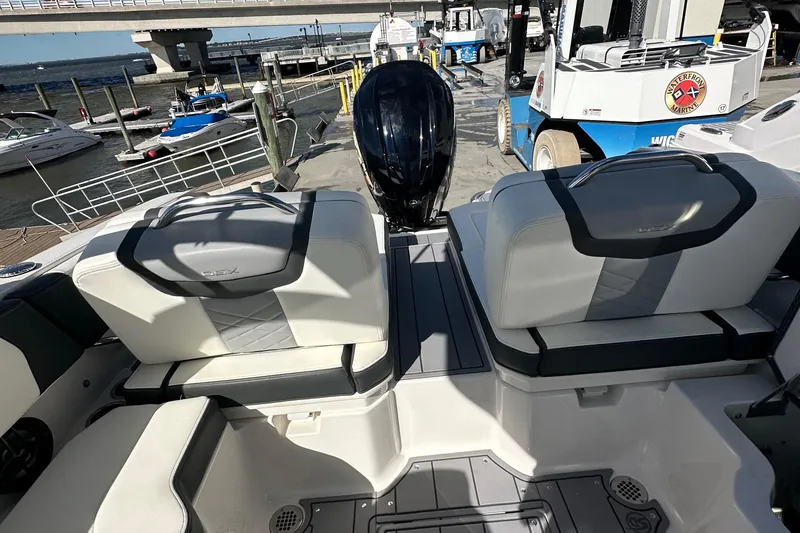Slide: The Image of 2023 Chaparral 250 OSX boat interior with seating and outboard motor at a marina. - 46