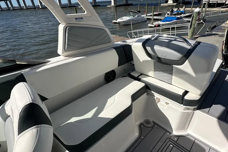 Slide: The Image of 2023 Chaparral 250 OSX boat interior with white seating, docked by the water. - 47