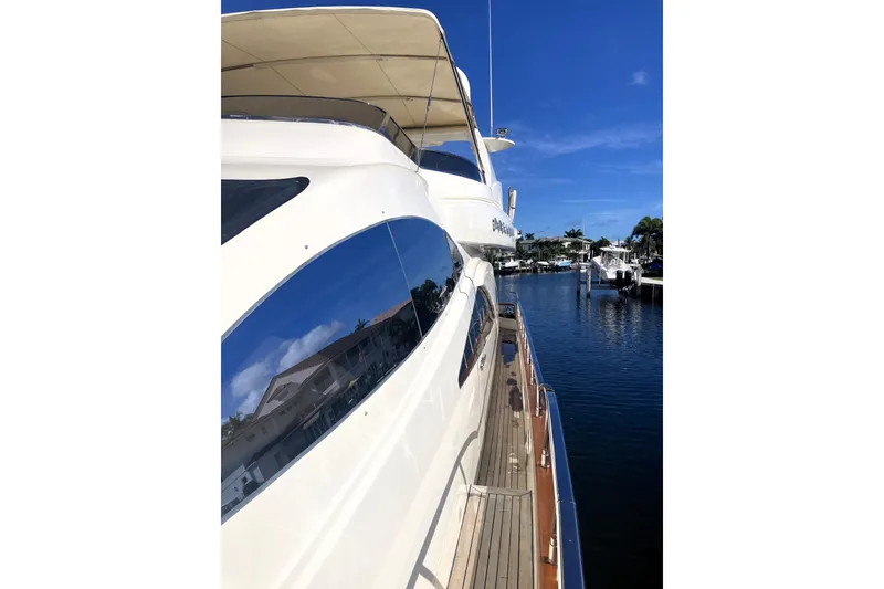 Slide: The Image of 2005 Azimut 80 Carat yacht docked, reflecting clear blue sky and waterfront homes. - 129