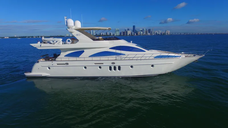 Slide: The Image of Luxury 2005 Azimut 80 Carat yacht cruising on open water with city skyline backdrop. - 11