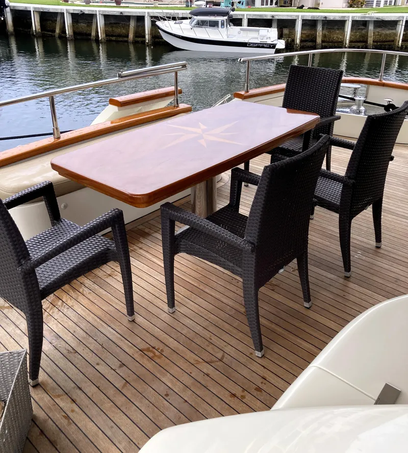 Slide: The Image of Outdoor dining area on 2005 Azimut 80 Carat yacht with wooden table and wicker chairs. - 16