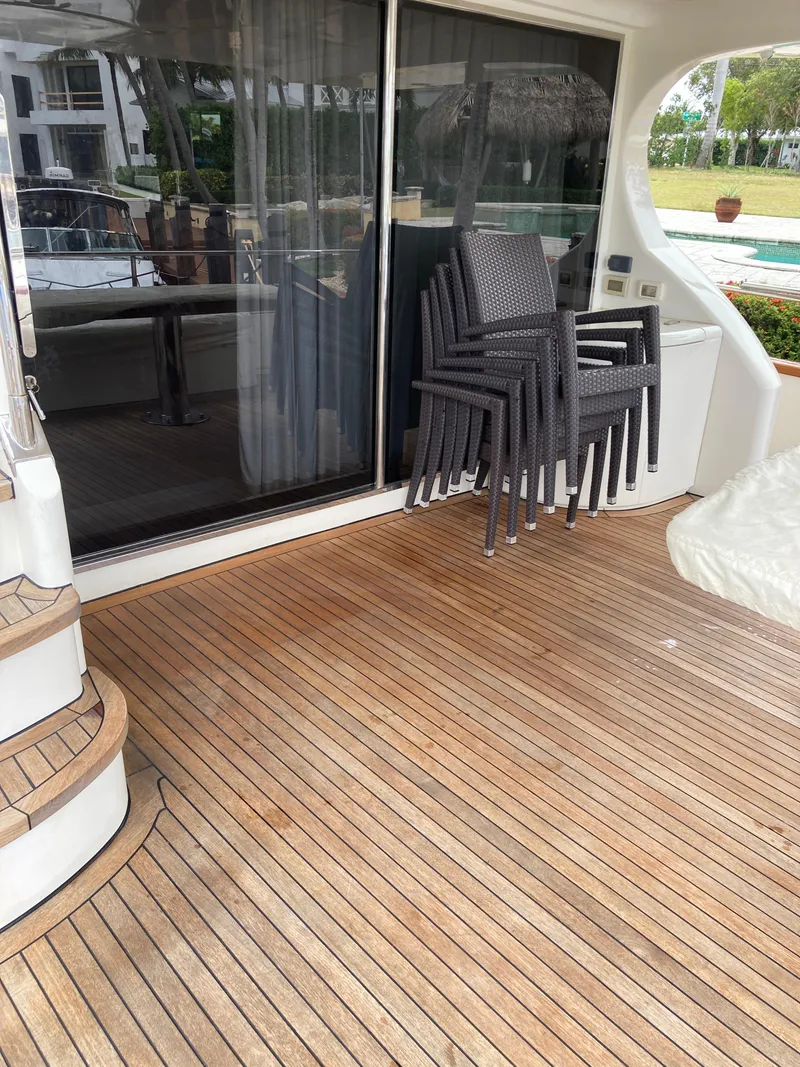 Slide: The Image of 2005 Azimut 80 Carat yacht deck with stacked chairs and wooden flooring. - 21