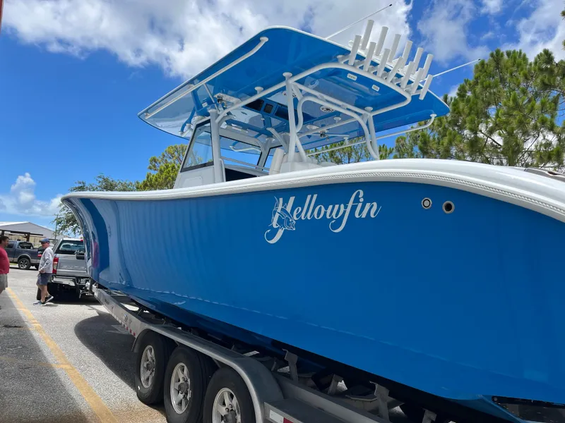 Slide: The Image of 2022 Yellowfin 39 Offshore boat on trailer, vibrant blue hull, clear sky background. - 2