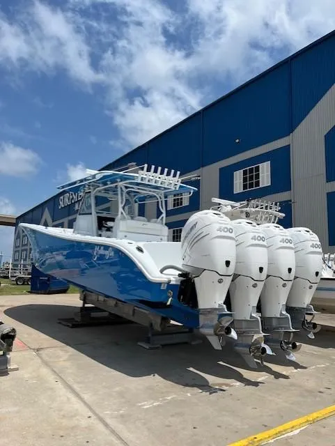 Slide: The Image of 2022 Yellowfin 39 Offshore boat with four powerful engines, parked near a blue building. - 7
