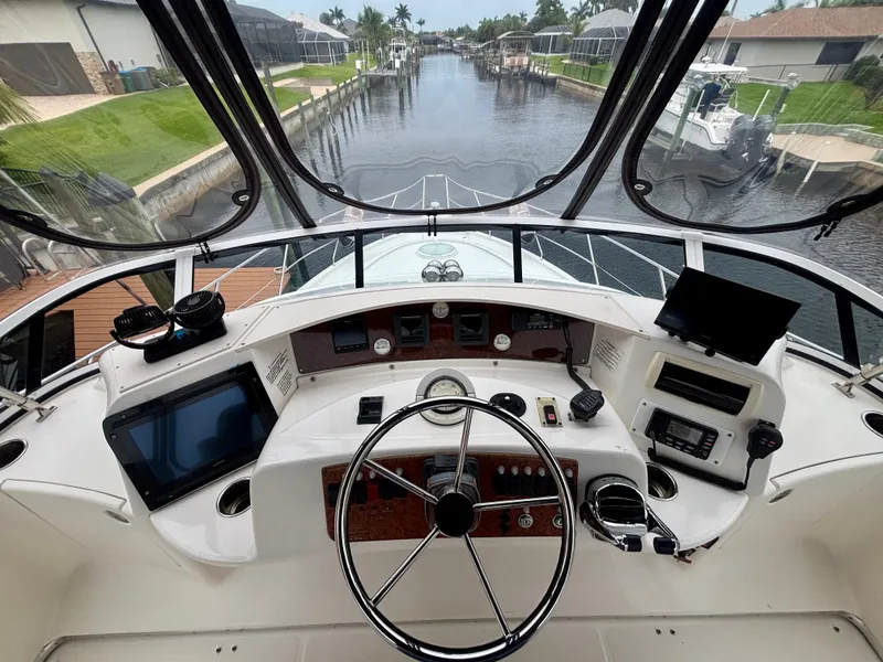 Slide: The Image of 2005 Silverton 39 Motor Yacht helm with steering wheel, navigation equipment, and canal view. - 21