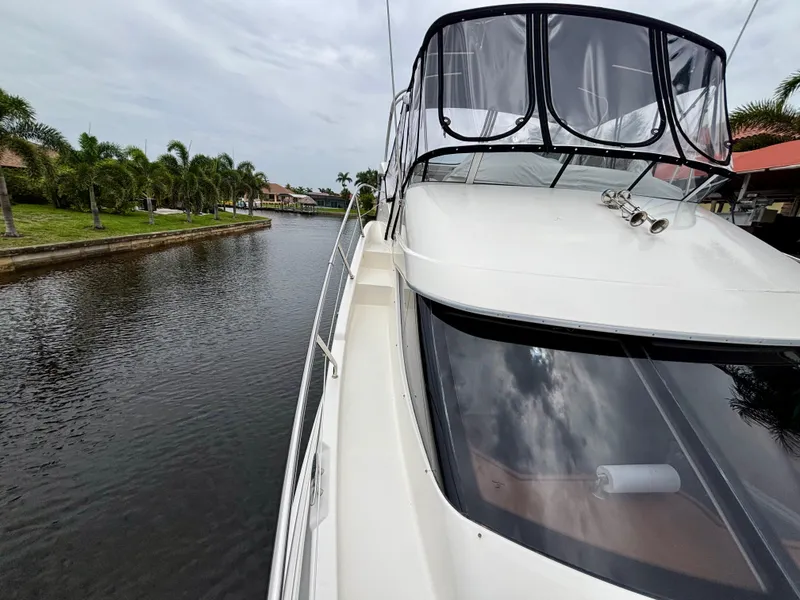 Slide: The Image of 2005 Silverton 39 Motor Yacht on a serene canal with palm trees. - 46