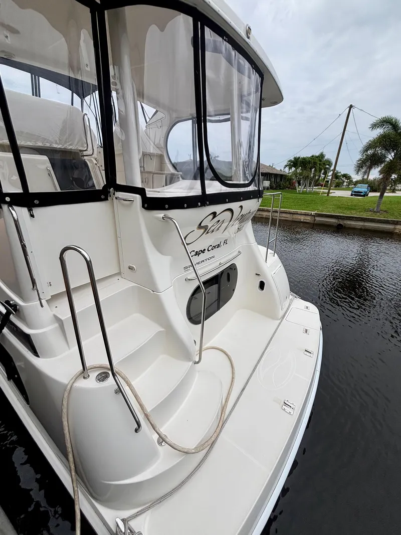 Slide: The Image of 2005 Silverton 39 Motor Yacht docked by a canal, featuring sleek design and spacious deck. - 5