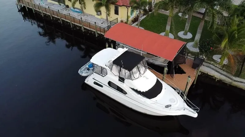 Slide: The Image of 2005 Silverton 39 Motor Yacht docked by a waterfront property with palm trees. - 6