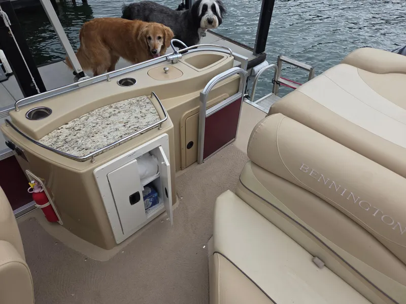 Slide: The Image of 2009 Bennington 2577RFSi boat interior with dogs, featuring seating and a kitchenette area. - 5