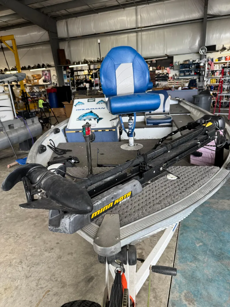 Slide: The Image of 1994 Grumman 1676B boat with blue seat and Minn Kota trolling motor in a workshop. - 11