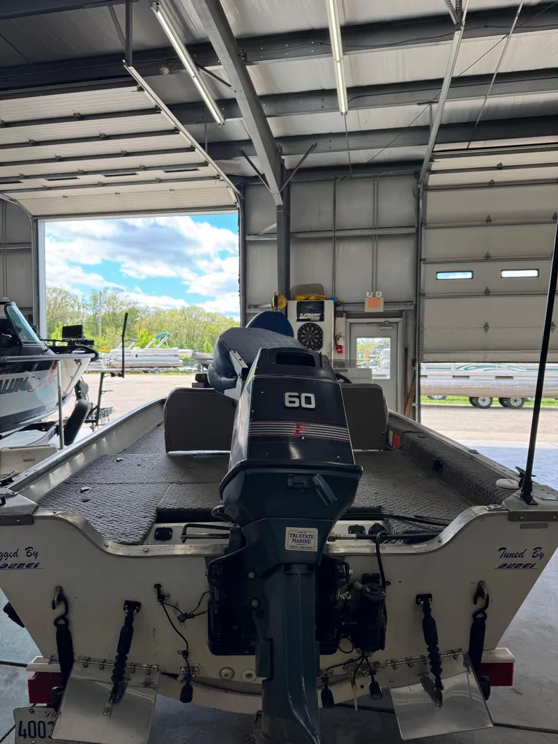 Slide: The Image of 1994 Grumman 1676B boat in garage, featuring a 60 HP outboard motor. - 12