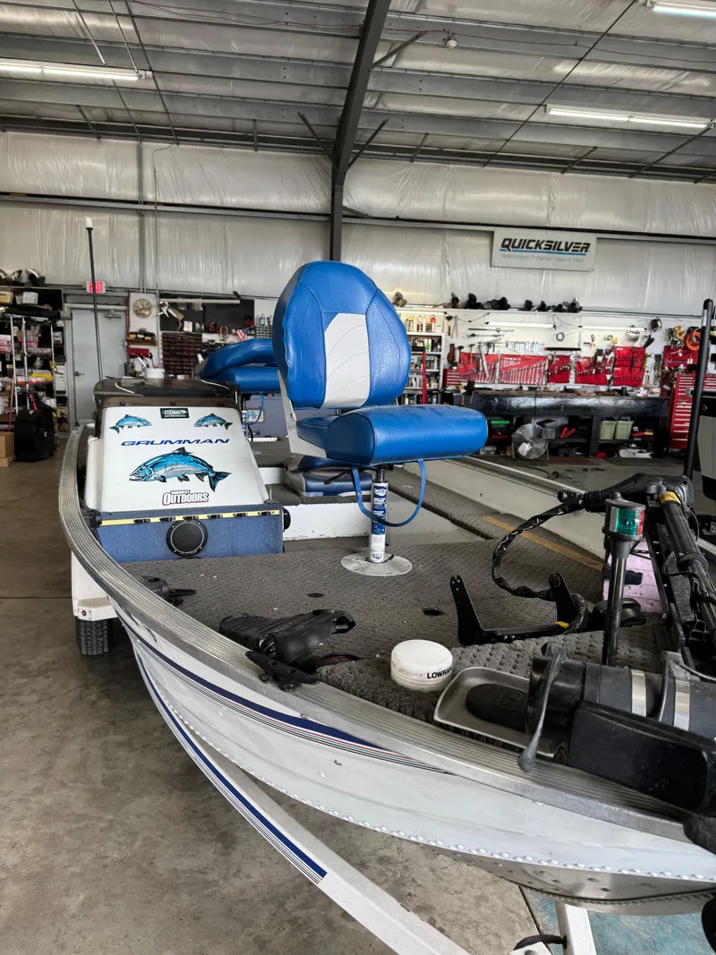 Slide: The Image of 1994 Grumman 1676B boat with blue seating in a workshop setting. - 4
