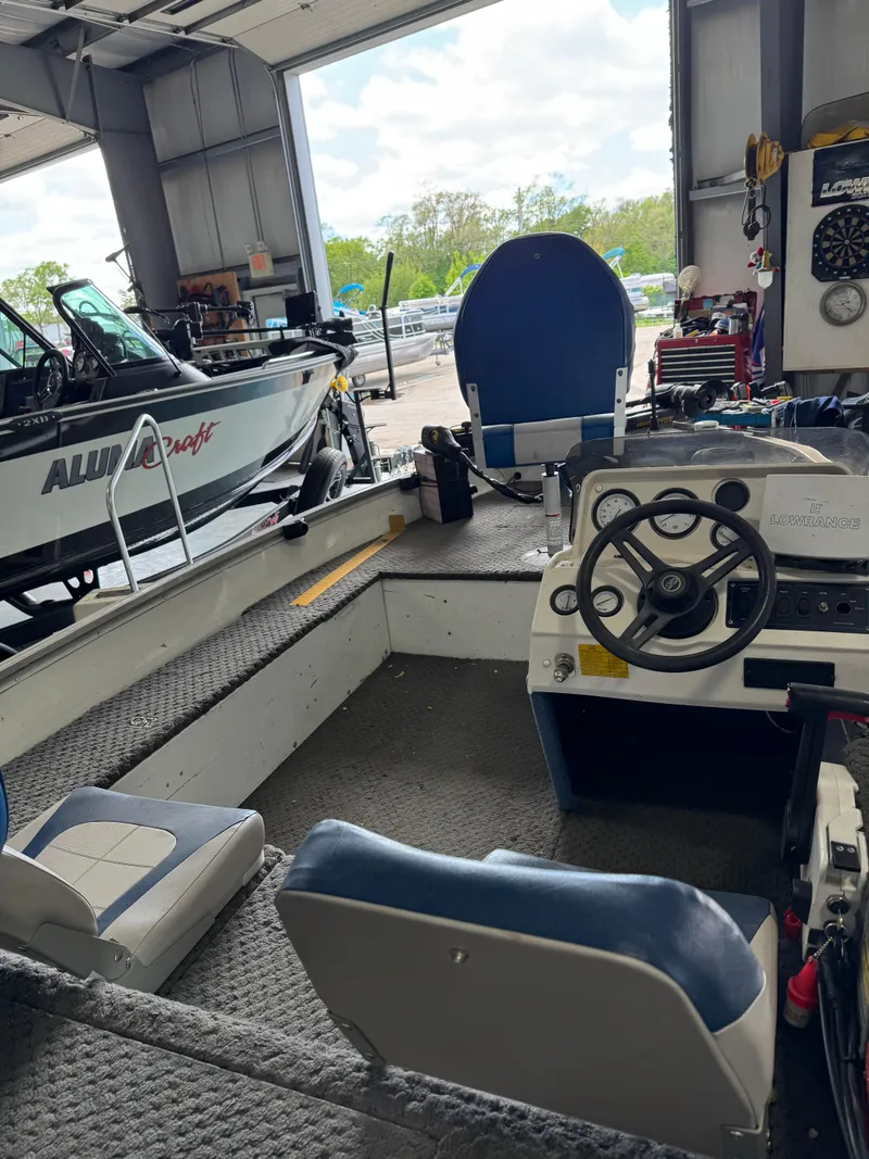 Slide: The Image of Interior of a 1994 Grumman 1676B boat in a garage with steering wheel and seating. - 6