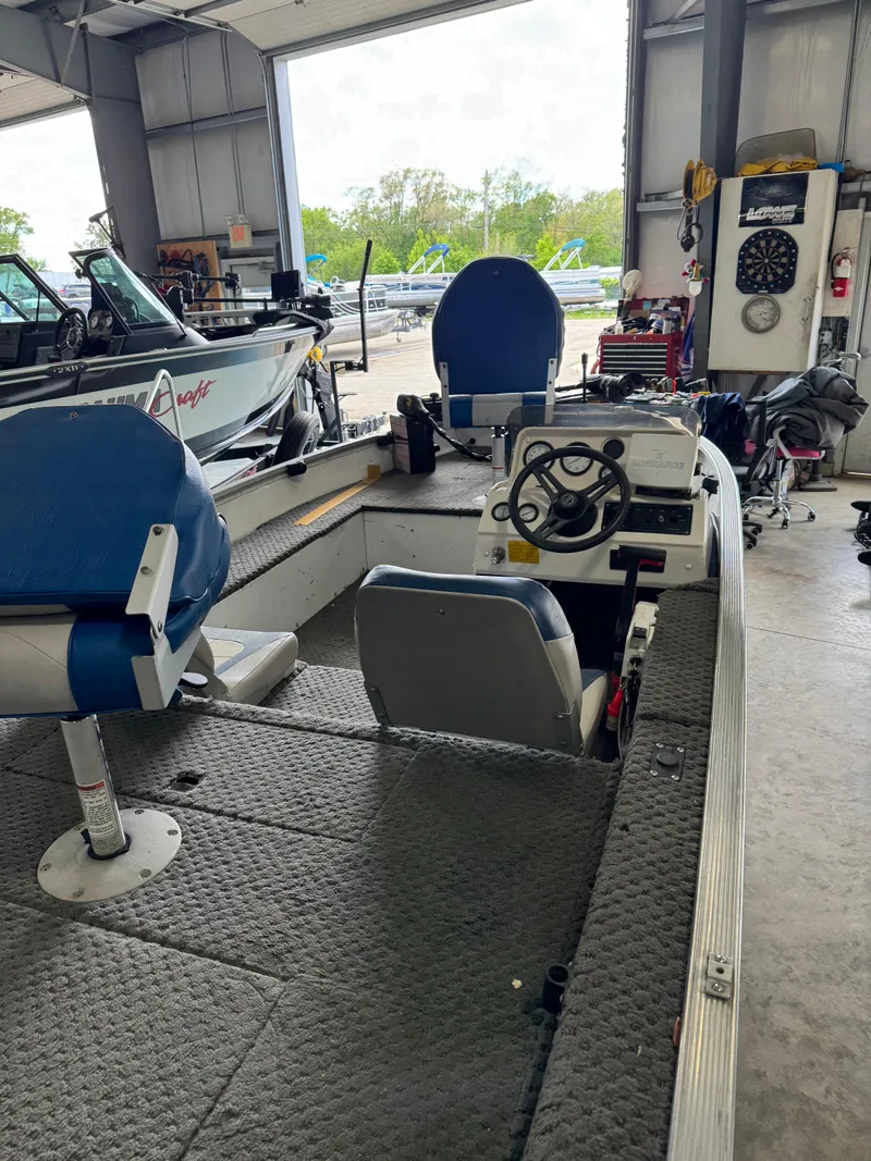 Slide: The Image of 1994 Grumman 1676B boat interior with blue seats in a garage setting. - 7