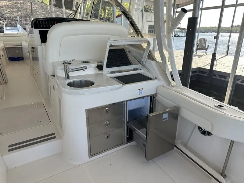 Slide: The Image of 2024 Grady-White Freedom 335 boat interior with kitchenette and storage, docked by the water. - 16