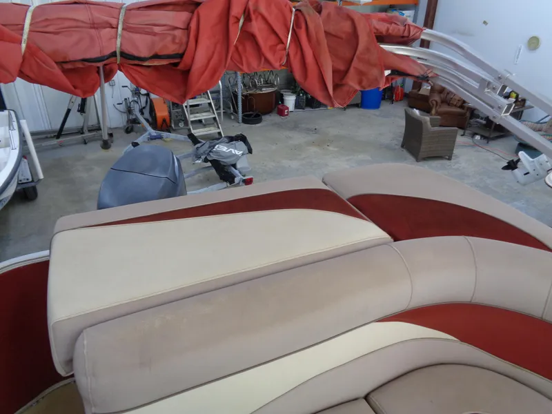 Slide: The Image of Sweetwater 2086 boat interior with red and beige seating, stored in a garage. - 10