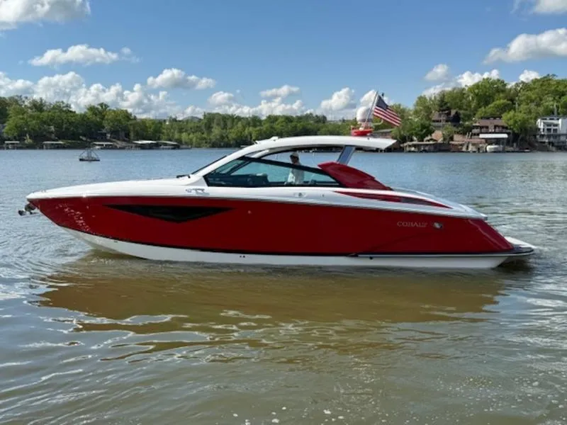 Slide: The Image of 2022 Cobalt A36BR boat on a lake, red and white design, clear sky background. - 2