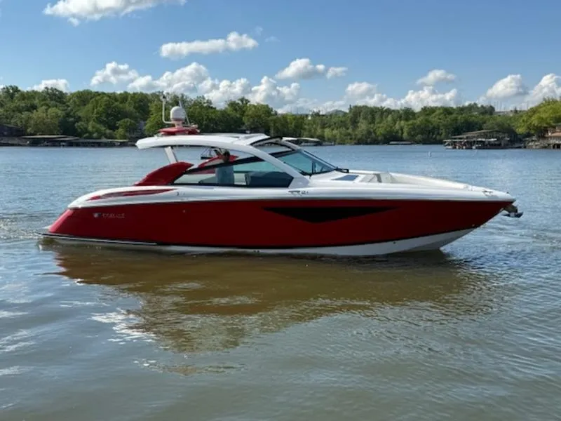 Slide: The Image of 2022 Cobalt A36BR boat in red on a calm lake with trees in the background. - 8