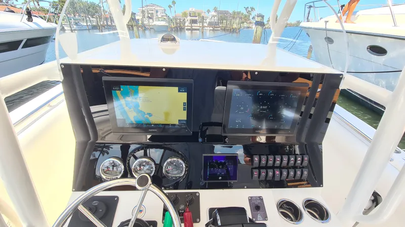 Slide: The Image of 2005 Marlago FS35 boat dashboard with navigation screens and controls, docked in a marina. - 16