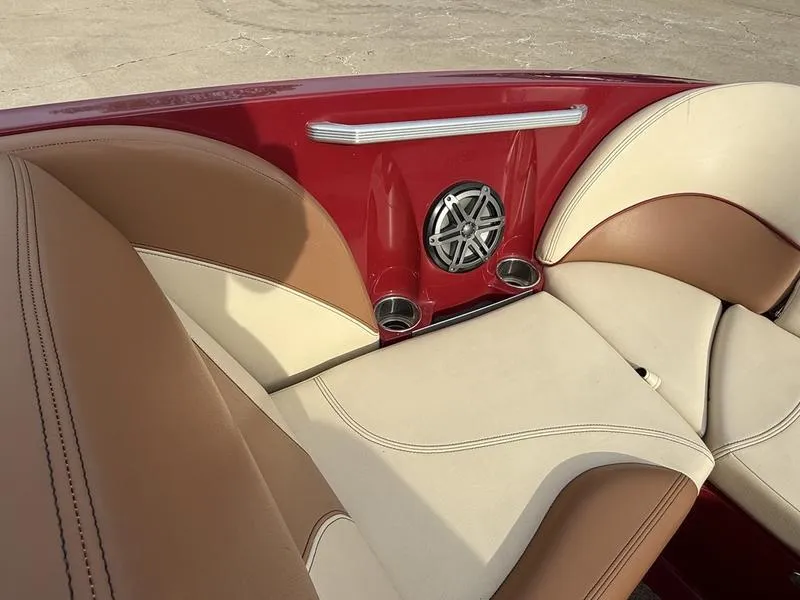 Slide: The Image of 2016 MasterCraft X23 boat interior with beige and brown seating, red accents, and speaker system. - 5