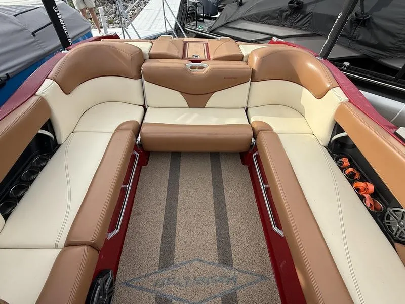 Slide: The Image of 2016 MasterCraft X23 boat interior with tan and cream seating, red accents, and cup holders. - 6