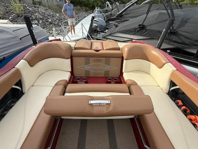 Slide: The Image of 2016 MasterCraft X23 boat interior with tan and cream seating, docked near other boats. - 7
