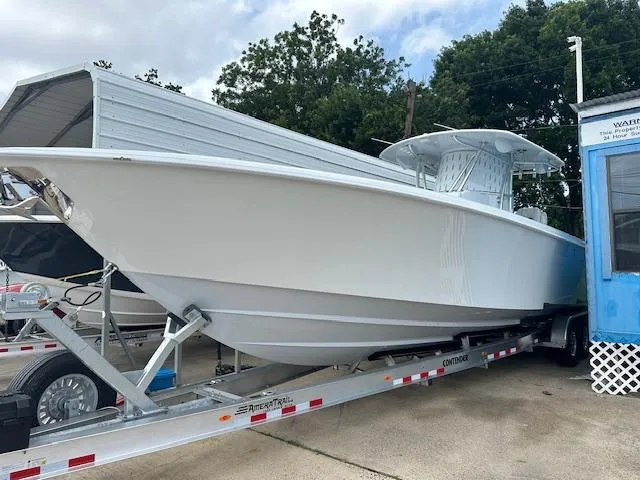 Slide: The Image of 2024 Contender 39 ST boat on trailer, parked outdoors near trees and buildings. - 1