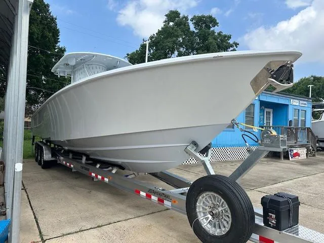Slide: The Image of 2024 Contender 39 ST boat on trailer, parked outdoors, under a partly cloudy sky. - 2