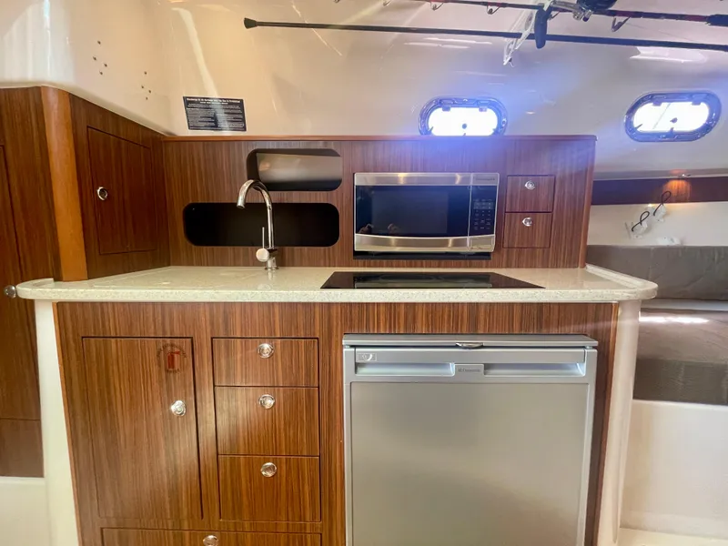 Slide: The Image of 2015 Pursuit 345 Offshore yacht kitchen with wood cabinetry, microwave, sink, and refrigerator. - 16
