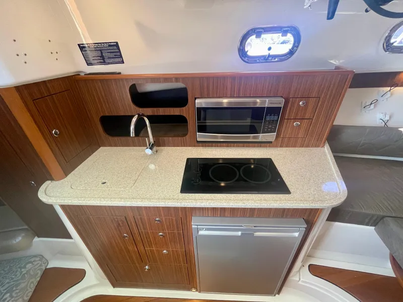 Slide: The Image of Compact kitchen in a 2015 Pursuit 345 Offshore boat with modern appliances and wood finish. - 17
