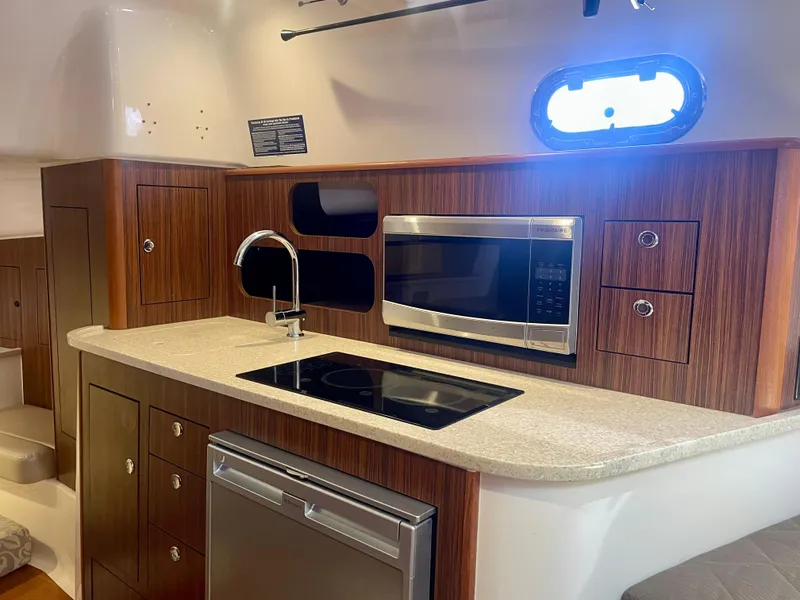 Slide: The Image of 2015 Pursuit 345 Offshore yacht kitchen with wood cabinets, microwave, and sink. - 18