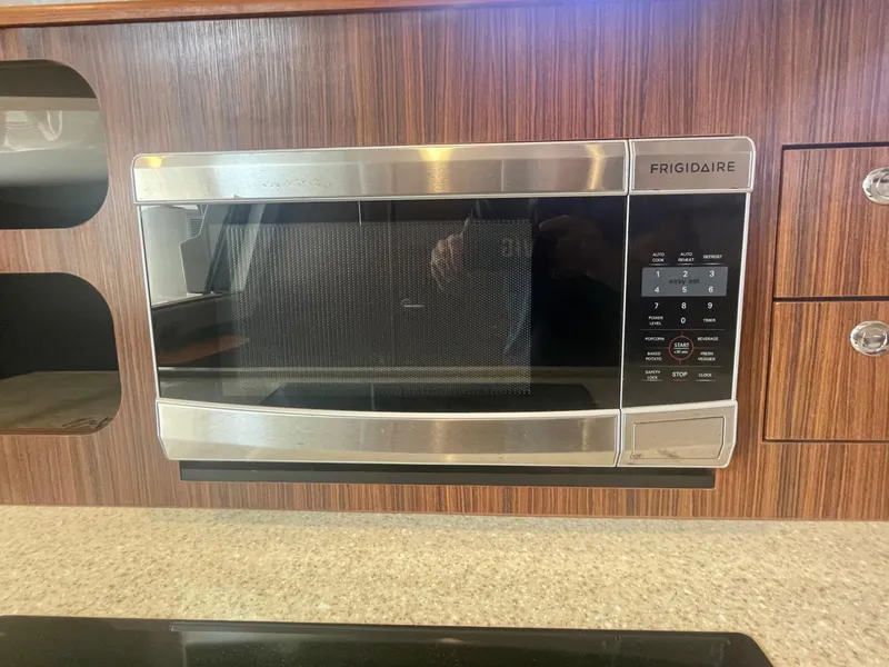 Slide: The Image of Frigidaire microwave in 2015 Pursuit 345 Offshore boat kitchen, wood paneling background. - 20