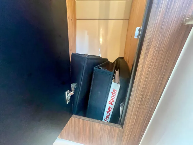 Slide: The Image of Open cabinet on 2015 Pursuit 345 Offshore boat with Fischer Panda manual inside. - 30