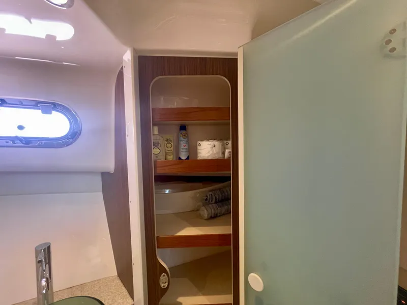 Slide: The Image of 2015 Pursuit 345 Offshore bathroom with shelves, toiletries, and a frosted glass door. - 34