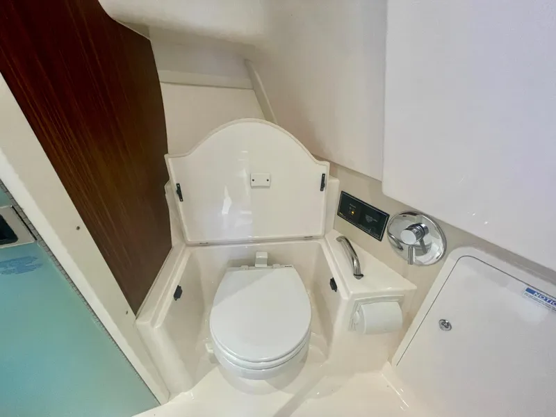 Slide: The Image of 2015 Pursuit 345 Offshore boat bathroom with toilet and storage compartments. - 35