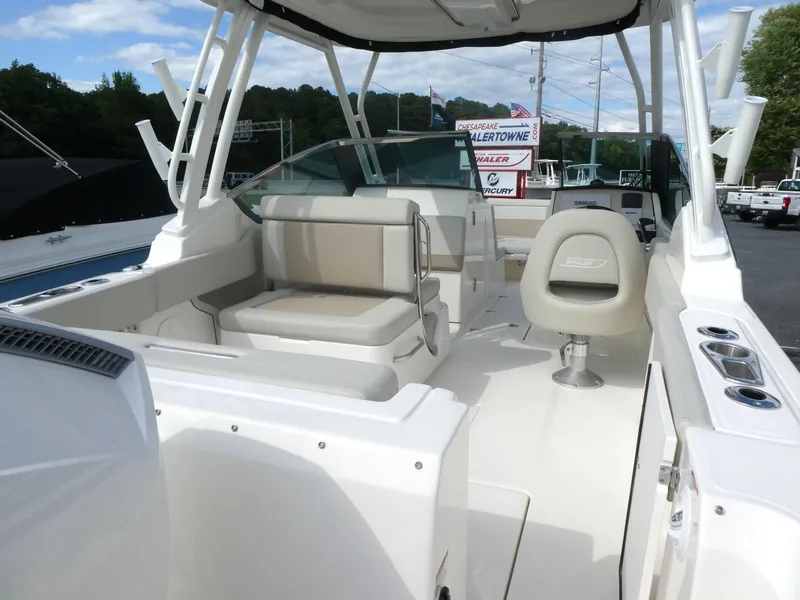 Slide: The Image of 2025 Boston Whaler 240 Vantage boat interior with seating and helm, under a clear sky. - 3