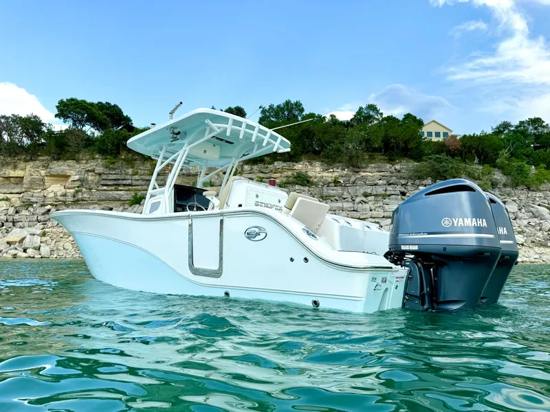 Slide: The Image of 2017 Sea Fox 288 Commander boat on water with Yamaha engine, rocky shoreline background. - 2