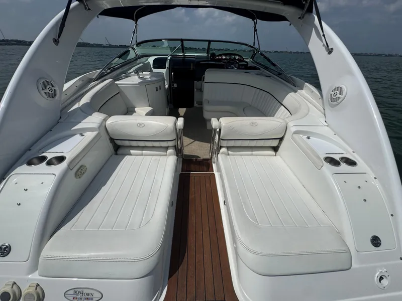 Slide: The Image of 2005 Cobalt 360 boat interior with white seating and wooden flooring, on a calm water backdrop. - 23