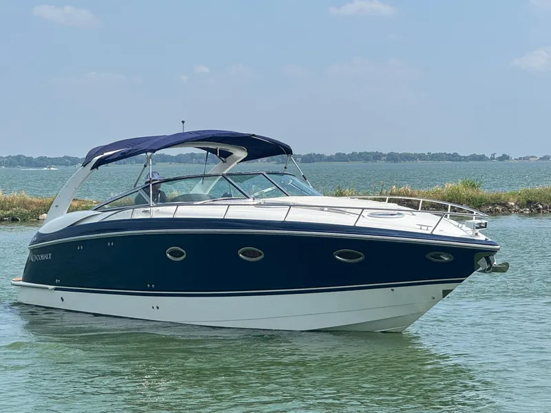 Slide: The Image of 2005 Cobalt 360 boat on water, blue and white design, clear sky background. - 3