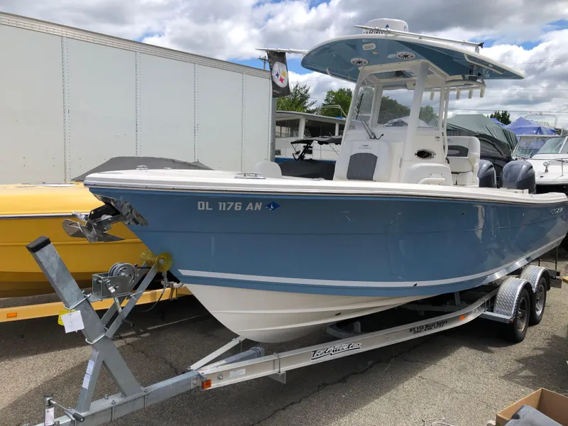Slide: The Image of 2021 Cobia 240 CC boat on trailer, blue hull, parked outdoors. - 0