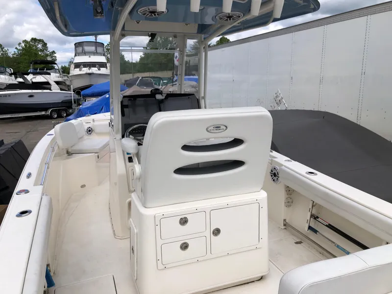 Slide: The Image of 2021 Cobia 240 CC boat interior with helm station and seating, docked near other boats. - 1