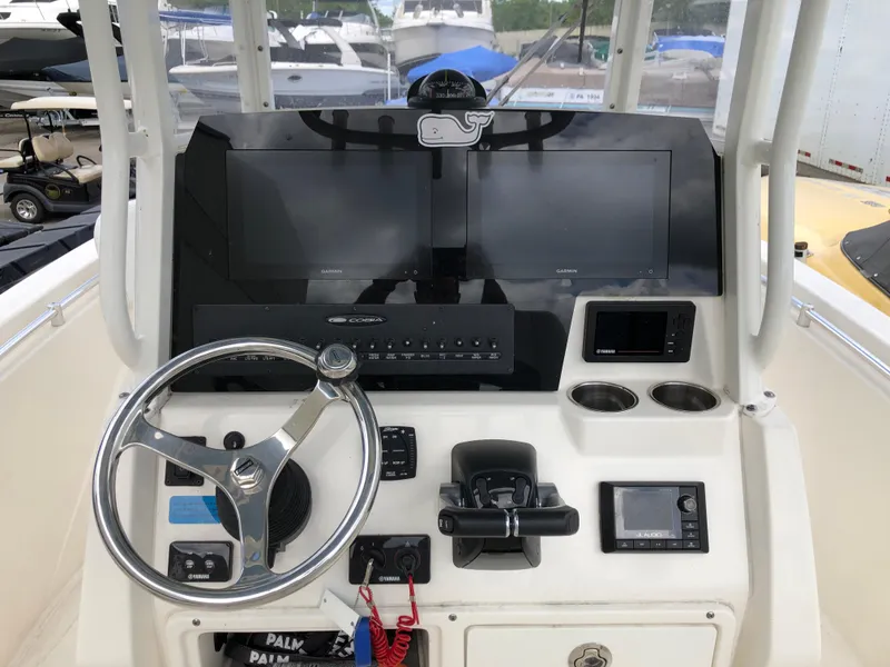 Slide: The Image of 2021 Cobia 240 CC boat dashboard with steering wheel, controls, and navigation screens. - 3