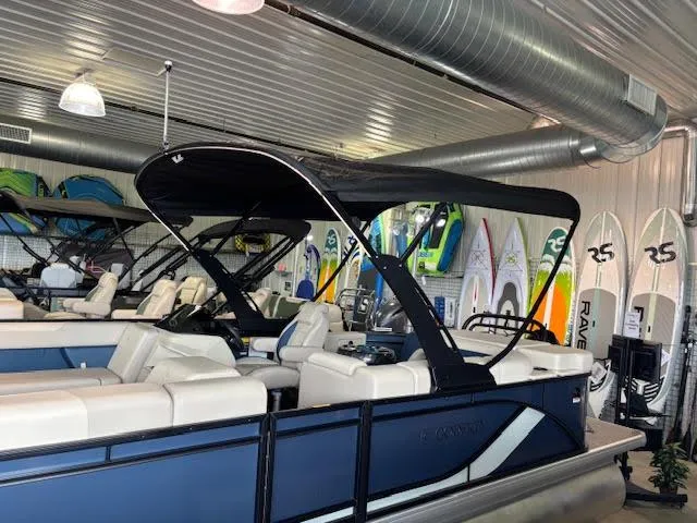 Slide: The Image of 2025 Godfrey SW2286CSE pontoon boat in showroom with surfboards in background. - 9