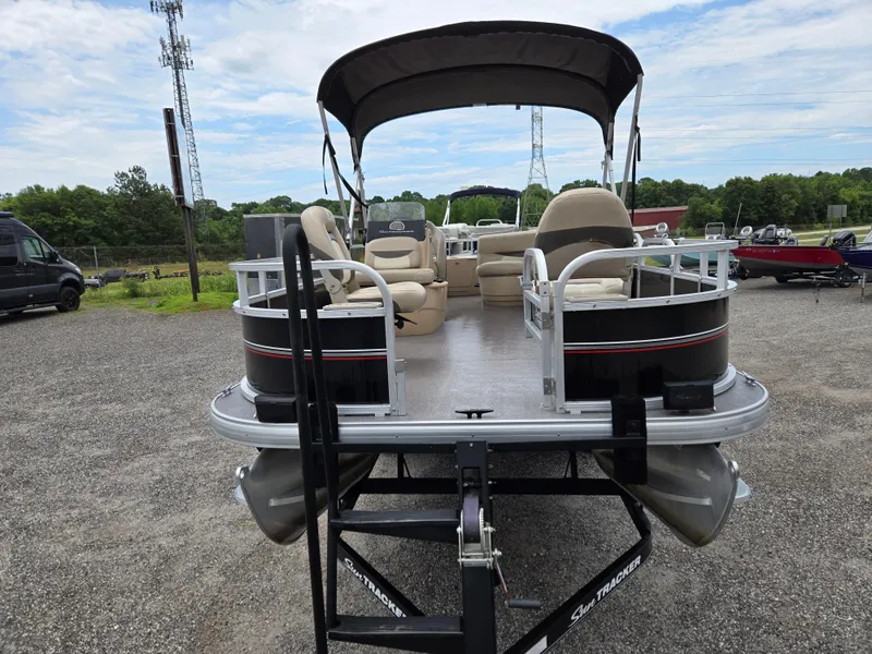 Slide: The Image of 2016 Sun Tracker Bass Buggy 18 DLX pontoon boat on trailer, parked outdoors. - 2